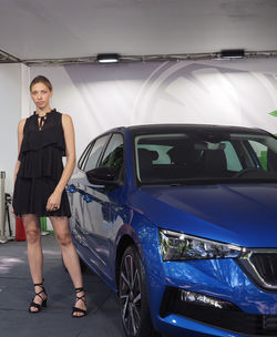 Full length portrait of woman standing by car