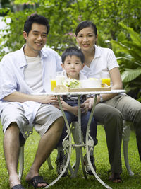 Portrait of parents having breakfast with son at backyard