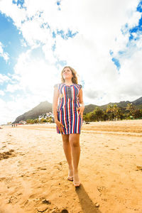 Full length of woman standing on beach against sky