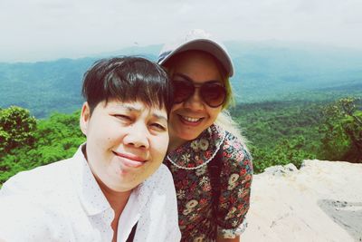 Portrait of smiling couple standing on mountain against sky