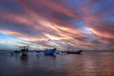 Boats moored on sea against sky during sunset