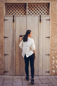 Full length of woman standing against door