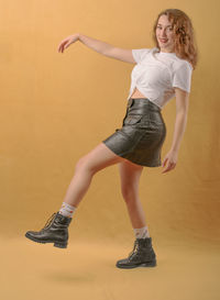 Full length portrait of woman standing against gray background