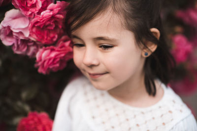 Beautiful kid girl 4-5 year old posing with pink roses outdoors closeup. childhood. summer season.