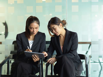 Businesswomen using digital tablet while sitting in office
