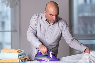 Man ironing clothes at home