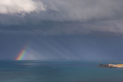 Scenic view of rainbow over sea against sky