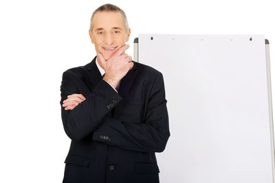 Portrait of businessman standing by whiteboard against white background