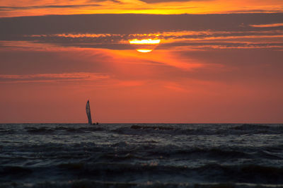 Silhouette of a sailboat from the evening beach at sunset time.
