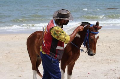 Rear view of woman riding horse on beach