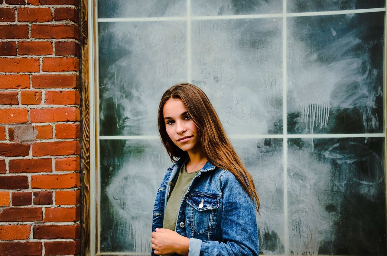 one person, wall, wall - building feature, young adult, real people, hair, brick, brick wall, lifestyles, standing, leisure activity, casual clothing, waist up, young women, architecture, hairstyle, built structure, front view, beautiful woman, outdoors