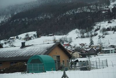 Snow covered houses by buildings against mountain