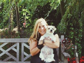 Portrait of woman with dog sitting outdoors