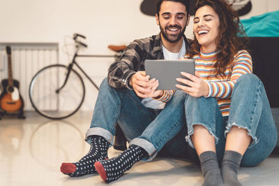 Smiling couple holding digital tablet sitting at home