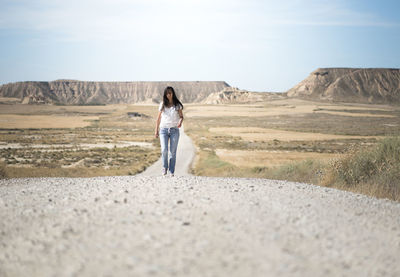 Full length of mature woman walking on road against sky during sunny day