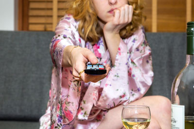 Midsection of woman holding drink while sitting on table