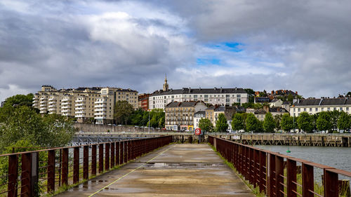 Bridge amidst buildings in city against sky