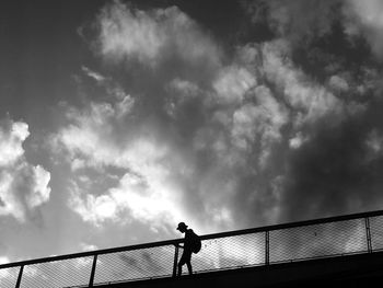 Low angle view of silhouette man standing on bridge against sky