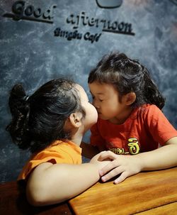 Close-up of siblings kissing while sitting at table