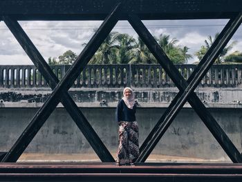 Portrait of woman standing at bridge against sky