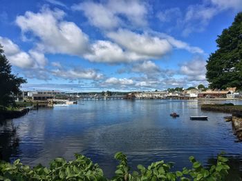 Boats in river against cloudy sky