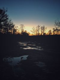 Silhouette bare trees on landscape against clear sky during sunset