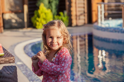 Portrait of smiling girl by swimming pool