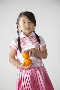 Cute girl holding oranges against white background