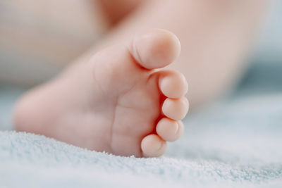 Foot with toes of sleeping caucasian newborn baby lying in bed on blue fleece blanket,side view. 