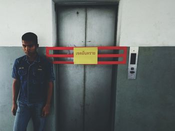 Man standing by text on wall