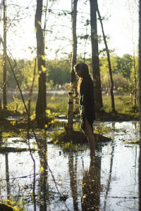 Side view of woman standing in lake at forest