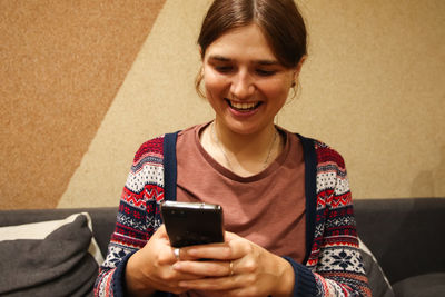 Happy millennial young woman checking social media holding smartphone at home. smiling young latin