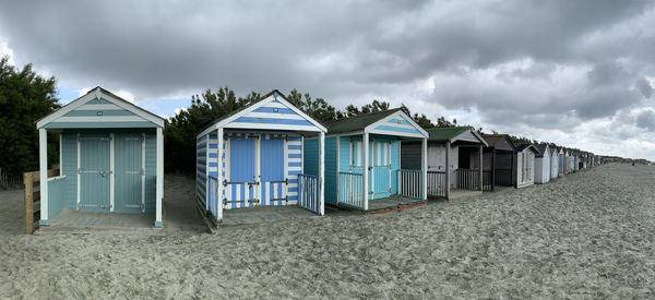 Beach huts by buildings against sky