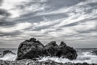 Rock formation in sea against sky