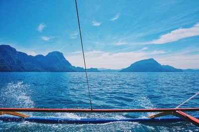 Boat in sea against blue mountains and sky