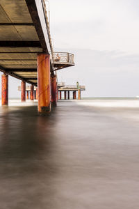 Pier on beach against sky