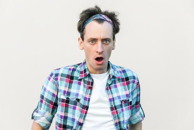 Portrait of young man standing against white background
