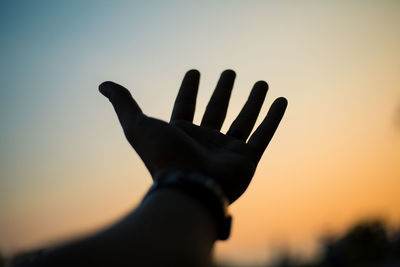 Close-up of silhouette hand against sky during sunset