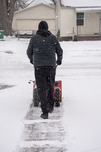 Man snow blows a driveway to clear the path after a heavy snow storm