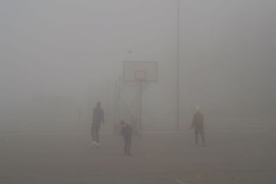 People playing soccer field during foggy weather