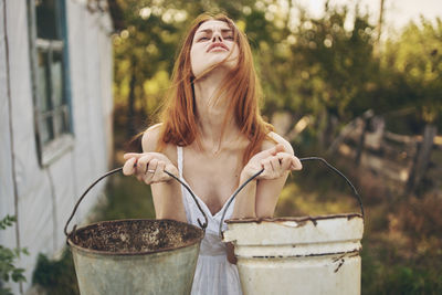 Woman holding buckets while standing outdoors