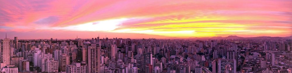 Panoramic view of city against dramatic sky during sunset