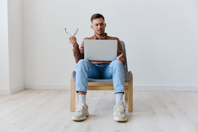 Woman using laptop while sitting on sofa at home