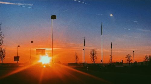 Street lights against orange sky during sunset