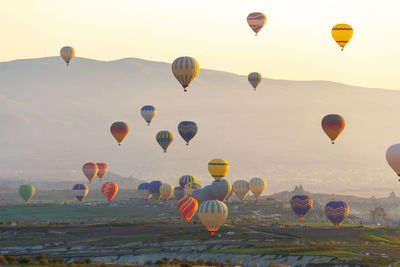 Hot air balloons flying over landscape against sky