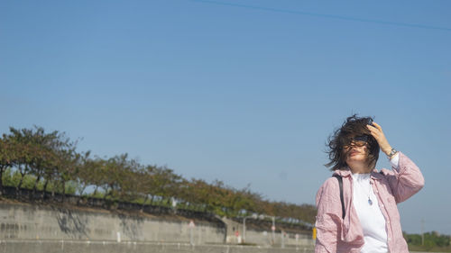 Young woman standing against river