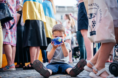 Rome, italy - may 22, 2022  a little ukrainian boy sitting on the ground at anti-war protest in rome