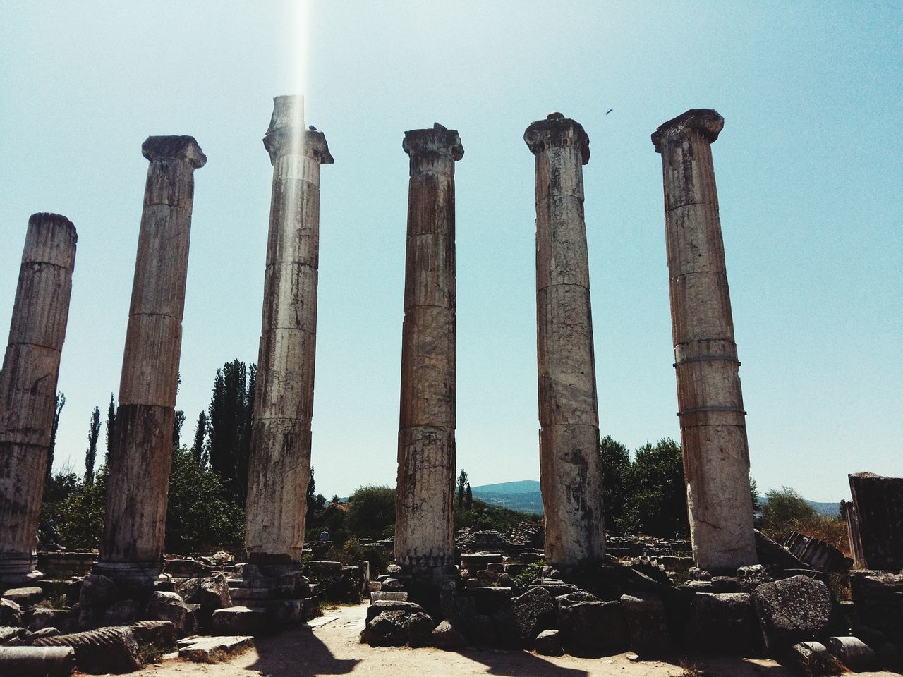 in a row, built structure, low angle view, architectural column, architecture, clear sky, column, factory, building exterior, sky, no people, sunlight, industry, day, outdoors, old ruin, old, the past, smoke stack, side by side