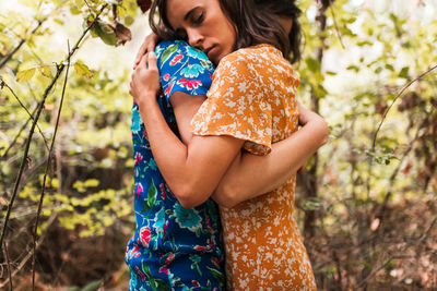 Young woman looking away while standing on tree