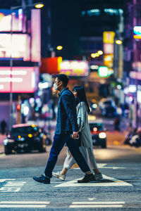 Side view of man walking on road at night